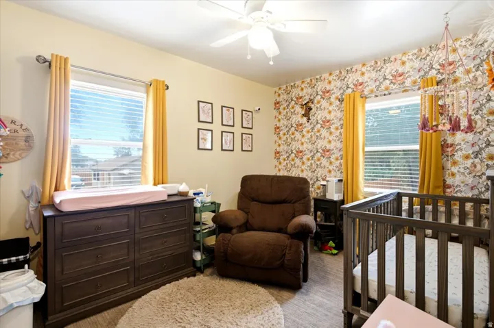 Interior space featuring light-toned walls, a decorative accent wall with floral pattern, and wood-finish flooring