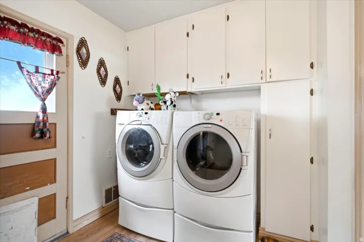White cabinetry with brass-finish hardware, wood-finish flooring, and a paneled door with window