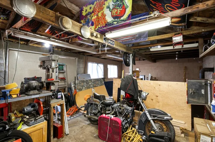 Utility room featuring exposed ceiling joists, fluorescent overhead lighting, and a concrete floor
