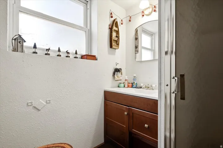 Bathroom featuring a white vanity with a built-in sink, wood-finish cabinetry, and a mirrored medicine cabinet