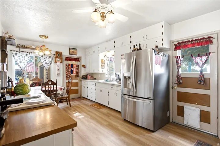 Kitchen featuring wood-finish flooring, white cabinetry, and a stainless steel refrigerator