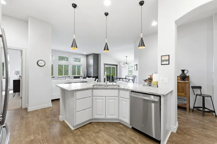 Kitchen island with white cabinetry, a stainless steel dishwasher, and a light-toned countertop