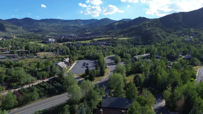 Expansive mountain landscape featuring lush green trees, paved roadways, and residential structures