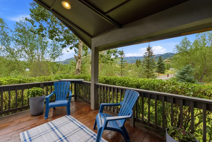 Covered patio featuring wood-finish flooring, dark wood railing, recessed ceiling lighting, and expansive mountain scenery