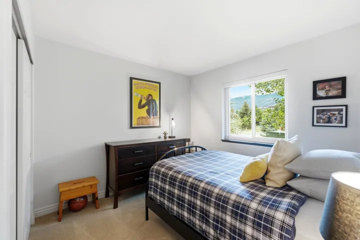 Bright room with white walls, carpet flooring, a window offering mountain scenery, and a sliding closet door