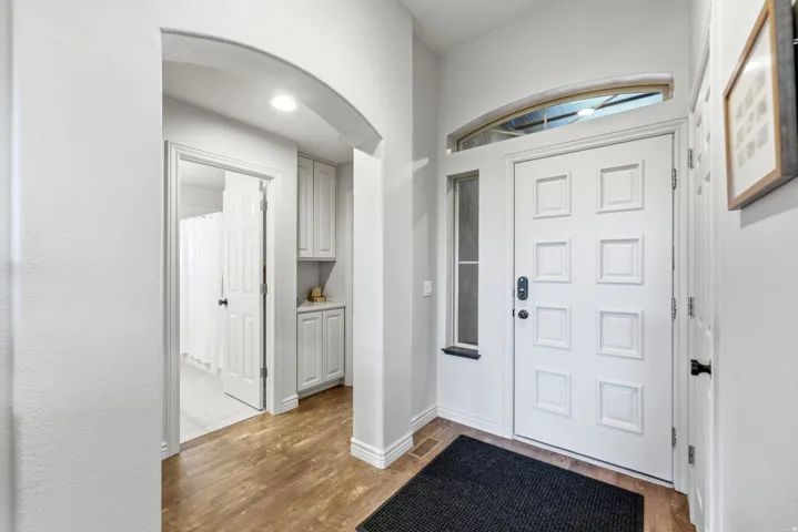 Entryway featuring a paneled door with transom window, wood-finish flooring, recessed lighting, built-in cabinetry, and an arched doorway