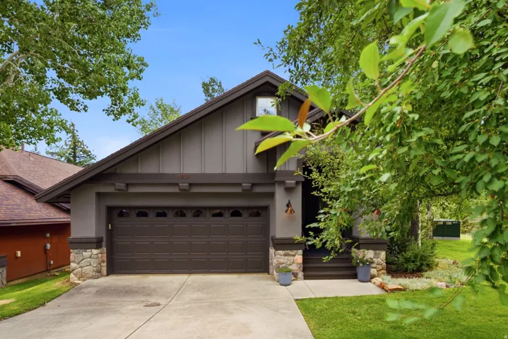Contemporary exterior featuring a two-car garage, stone accent pillars, and a gabled roofline