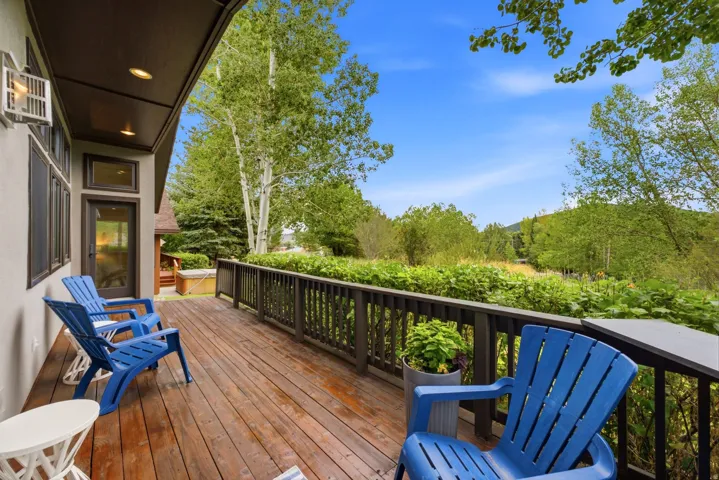 Expansive outdoor deck featuring wood-finish flooring, dark wood railings, and an integrated hot tub structure
