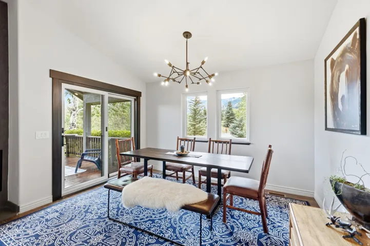 Dining area featuring a contemporary chandelier, white walls, and a patterned area rug