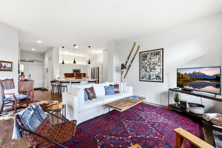 Open-concept living area featuring wood-finish flooring, recessed lighting, and a white paneled entry door