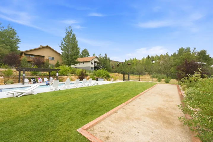 Spacious outdoor area featuring a swimming pool, adjacent paved patio, and a dedicated bocce ball court
