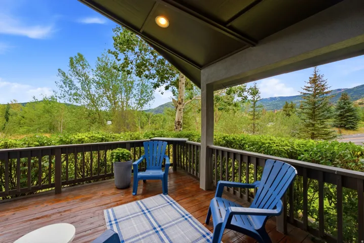 Covered outdoor deck featuring wood-finish flooring and a dark wood railing