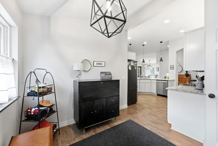 Entryway featuring a geometric pendant light fixture, wood-finish flooring, and bright white walls