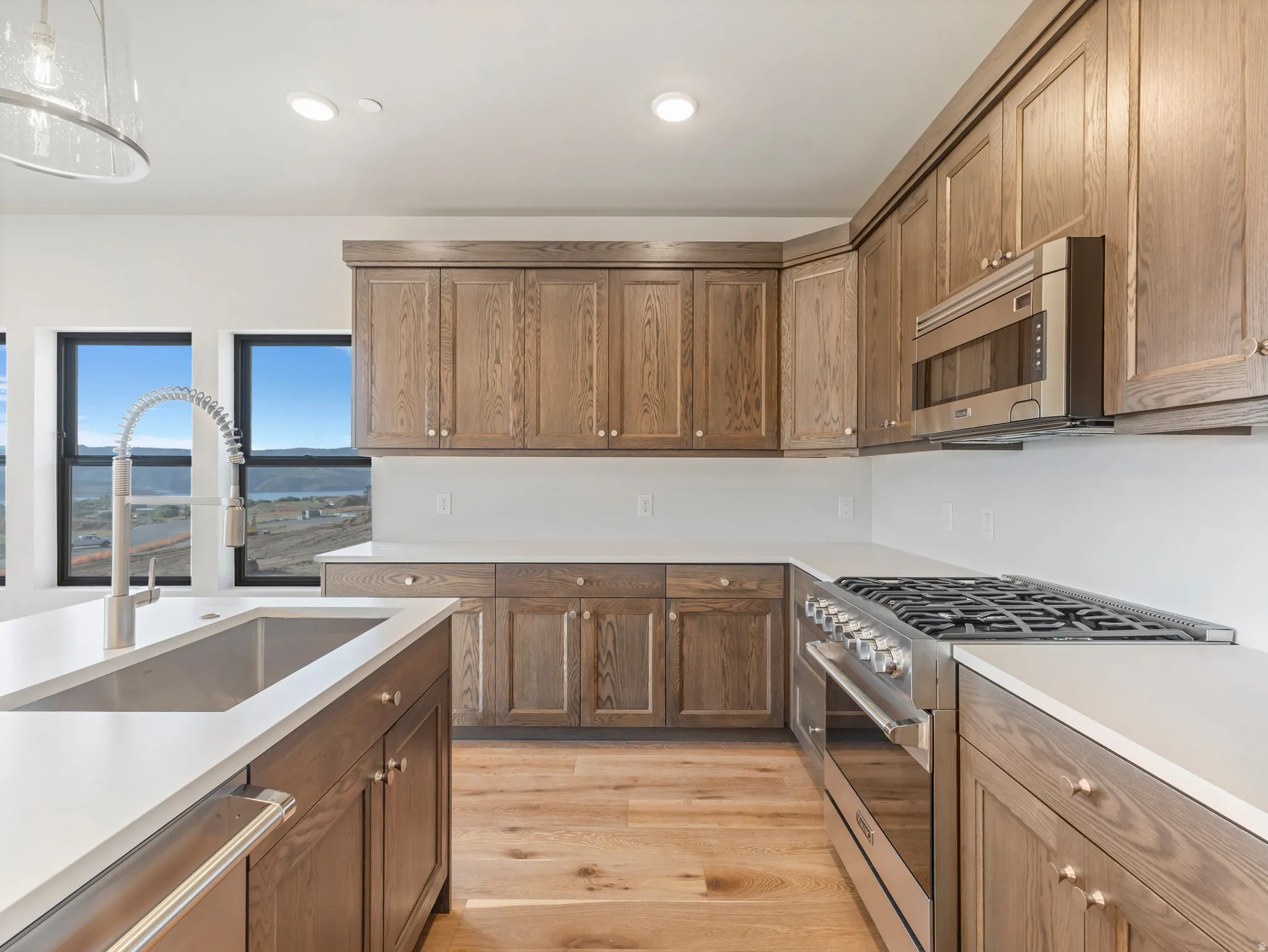 Kitchen featuring wood cabinetry, stainless steel appliances, white countertops, and wood-finish flooring