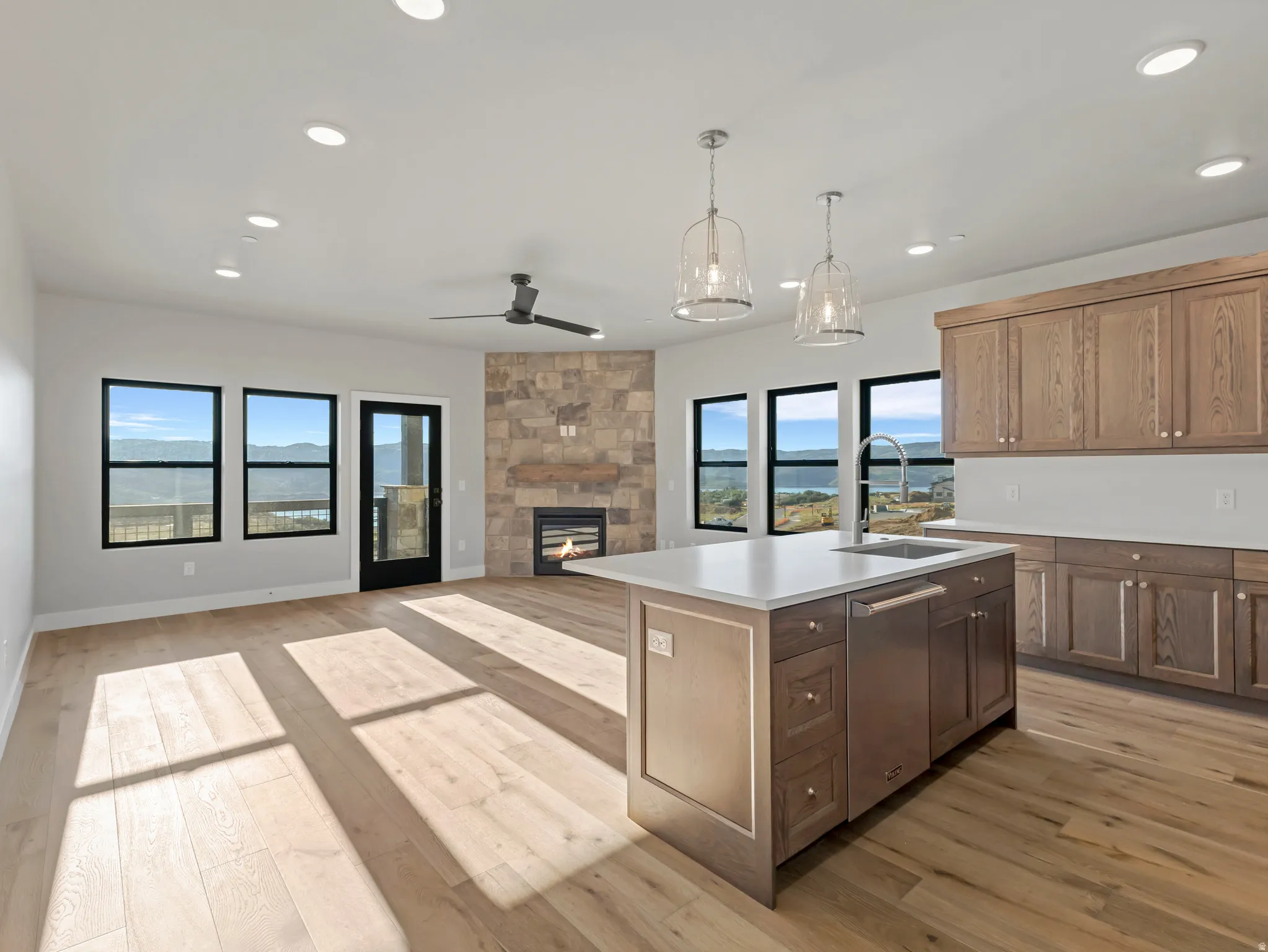 Open-concept great room featuring a central kitchen island with a built-in sink, stainless steel dishwasher, and pendant lighting