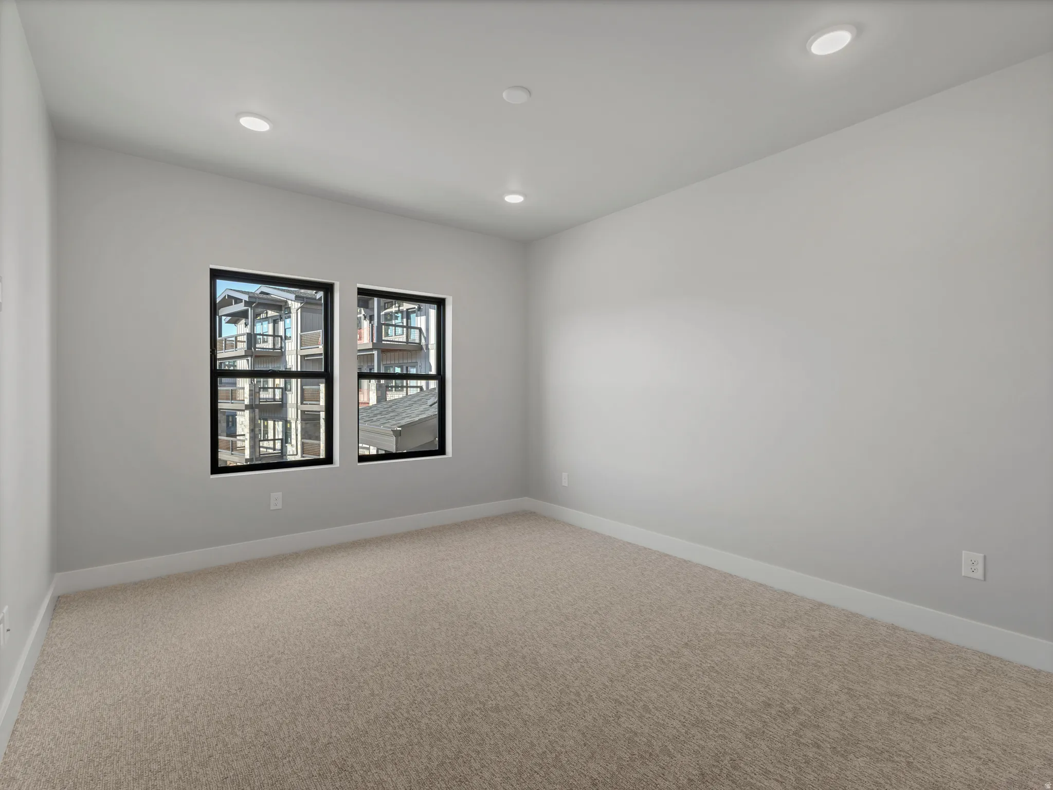 Neutral-toned room featuring a light beige carpet, white baseboards, and light gray painted walls