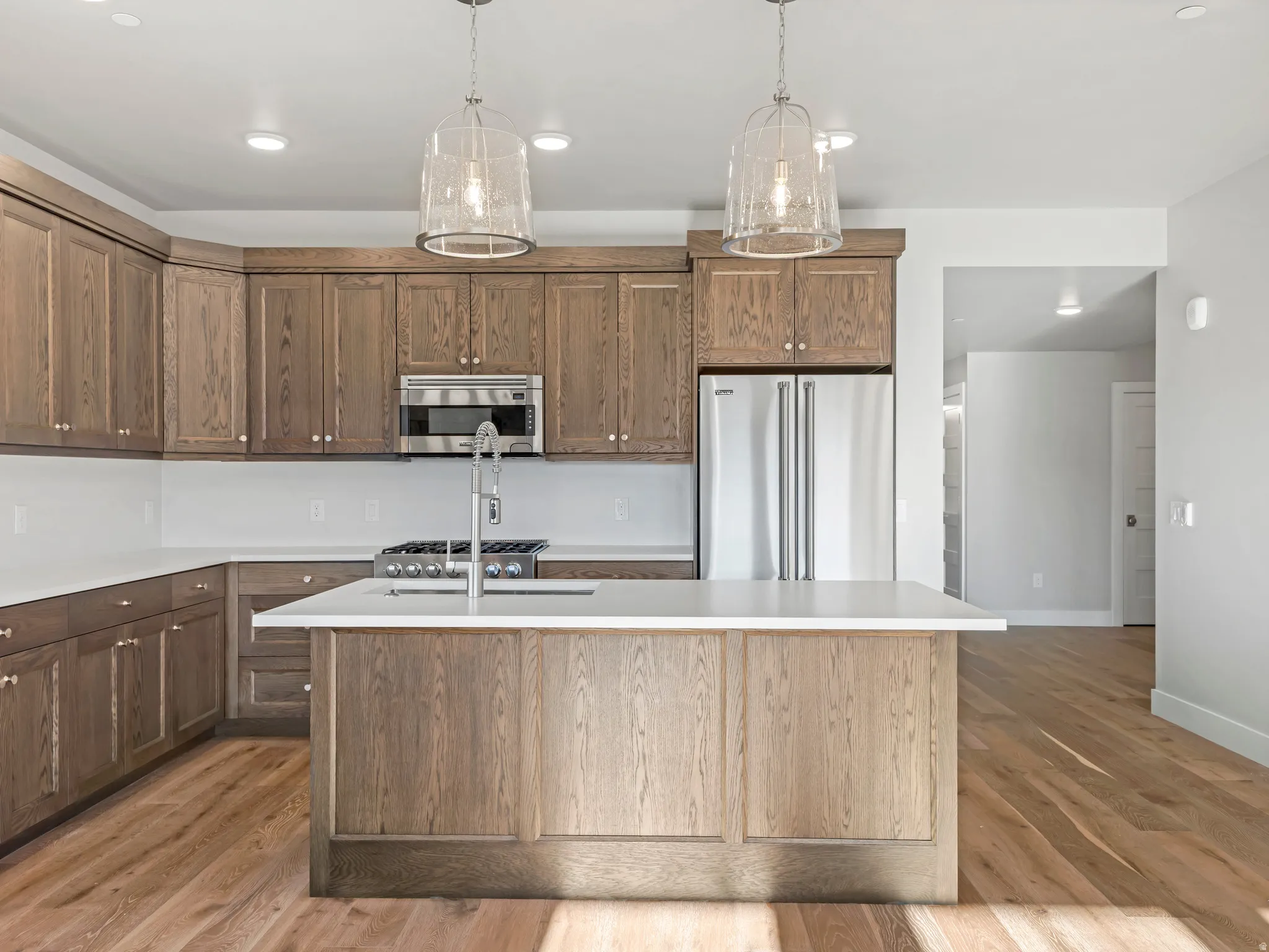Modern kitchen featuring wood-finish cabinetry, stainless steel appliances, a center island with countertop seating, recessed lighting, and wood-finish flooring