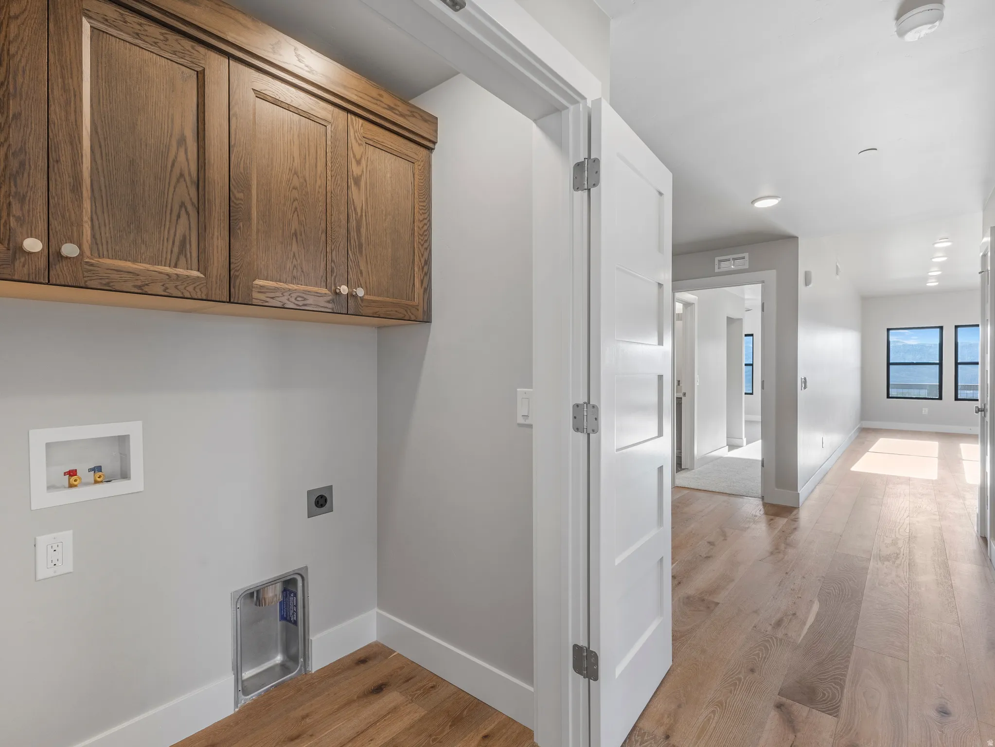 Dedicated laundry space featuring wood cabinetry and white trim