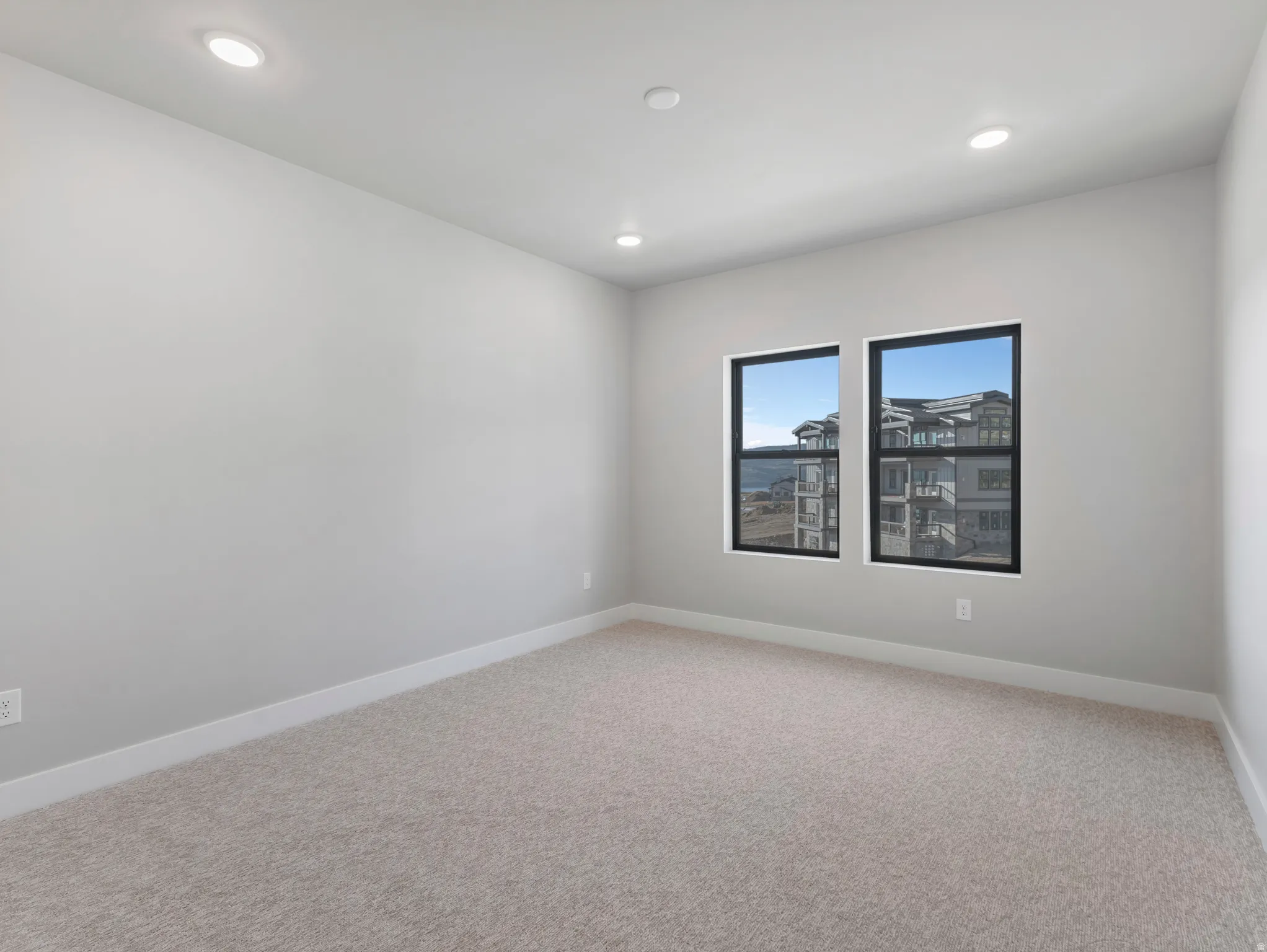 Recessed lighting illuminates this room featuring wall-to-wall carpeting and contemporary windows with black frames
