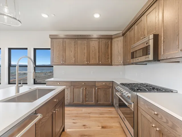 Kitchen featuring wood cabinetry, stainless steel appliances, white countertops, and wood-finish flooring