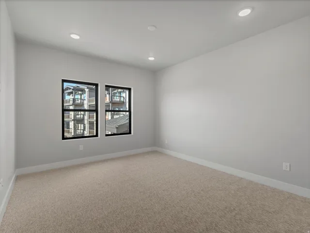 Neutral-toned room featuring a light beige carpet, white baseboards, and light gray painted walls