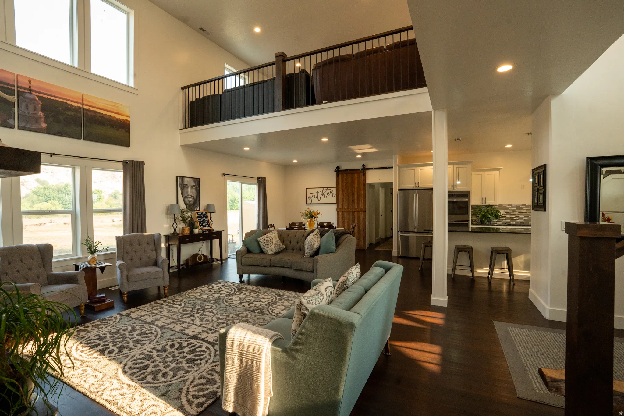 Soaring two-story great room with hardwood flooring, recessed lighting, and a mezzanine-level loft overlooking the main living space