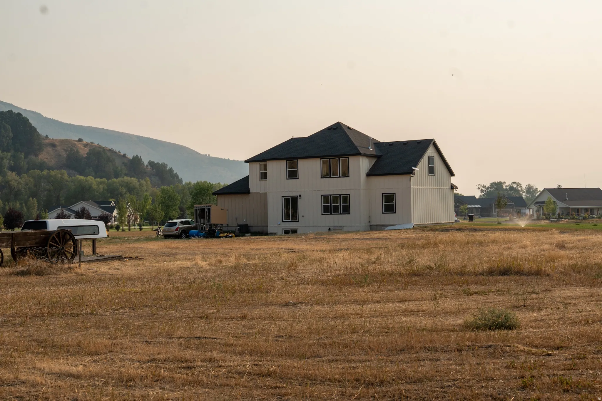 Two-story residence featuring white vertical and horizontal siding, a dark shingle roof, and dark-framed windows