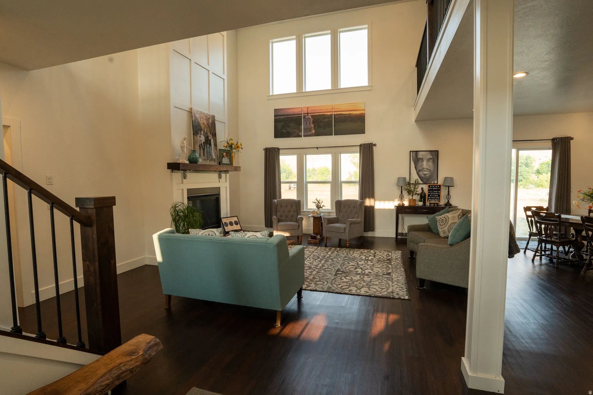 Spacious living area featuring a two-story ceiling, dark wood-finish flooring, and a fireplace with a decorative mantel and surround