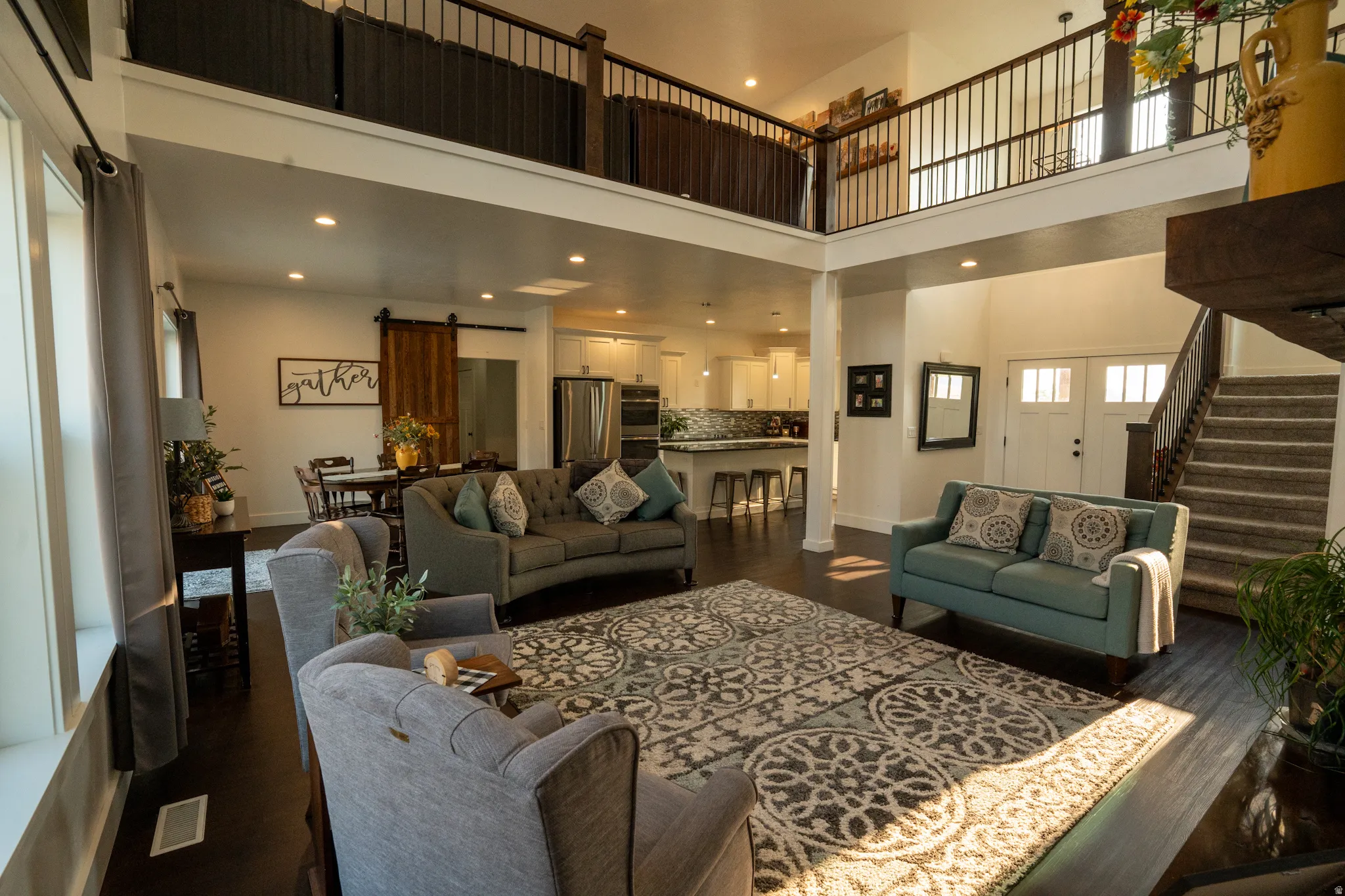 Open-concept living space featuring soaring two-story ceilings, recessed lighting, and a mezzanine-level railing