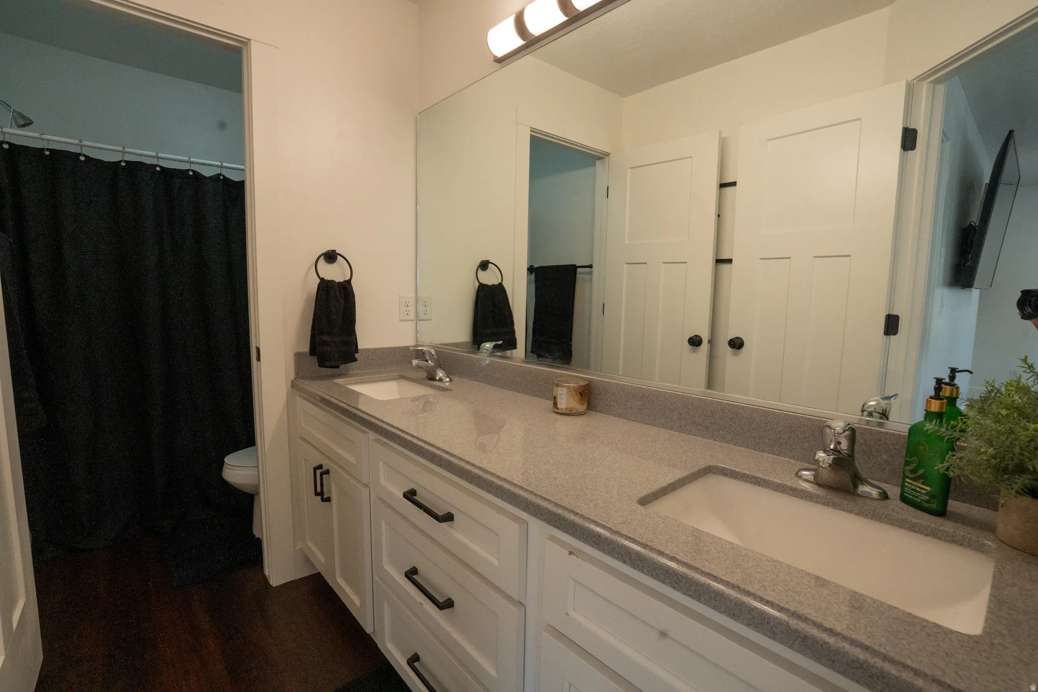 Spacious primary bathroom featuring a dual-sink vanity with white cabinetry, quartz countertops, and an undermount sink design
