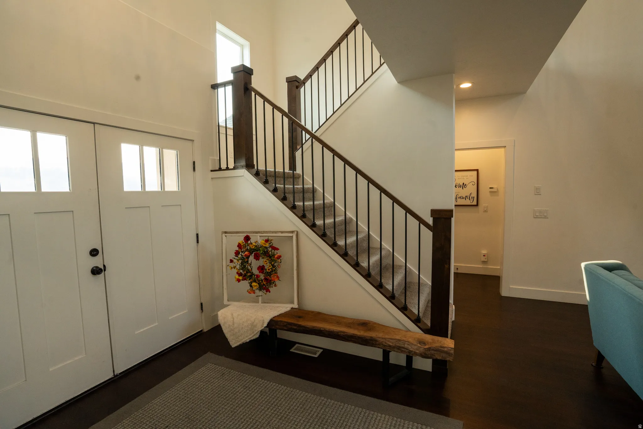 Welcoming foyer showcasing a dramatic open staircase with dark wood railings and metal balusters, illuminated by natural light from transom windows