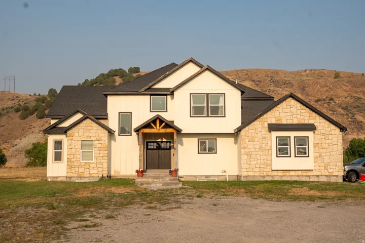 Contemporary two-story residence featuring a striking mixed-material exterior combining cream-colored siding with stone accents