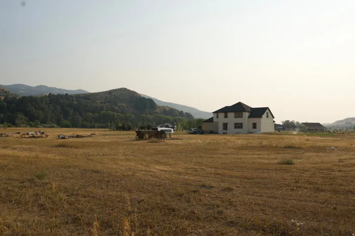 Expansive rural property featuring a two-story residence with a light-colored exterior and pitched roof set on substantial acreage
