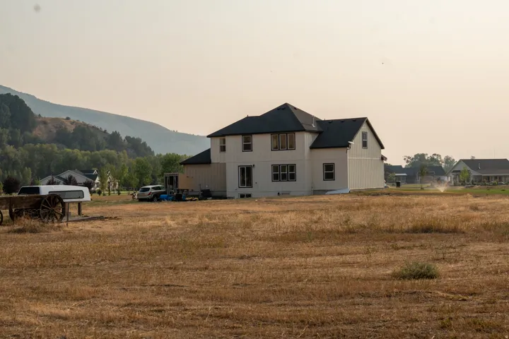 Two-story residence featuring white vertical and horizontal siding, a dark shingle roof, and dark-framed windows