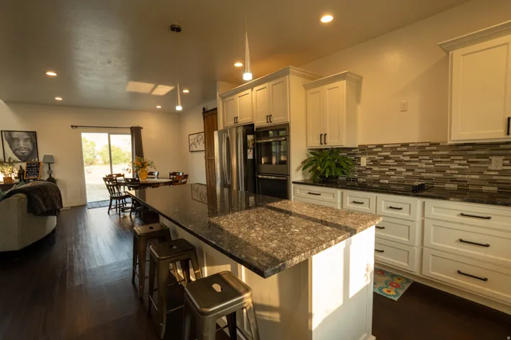 Gourmet kitchen featuring cream-colored cabinetry with hardware accents, granite countertops, and a large center island with seating