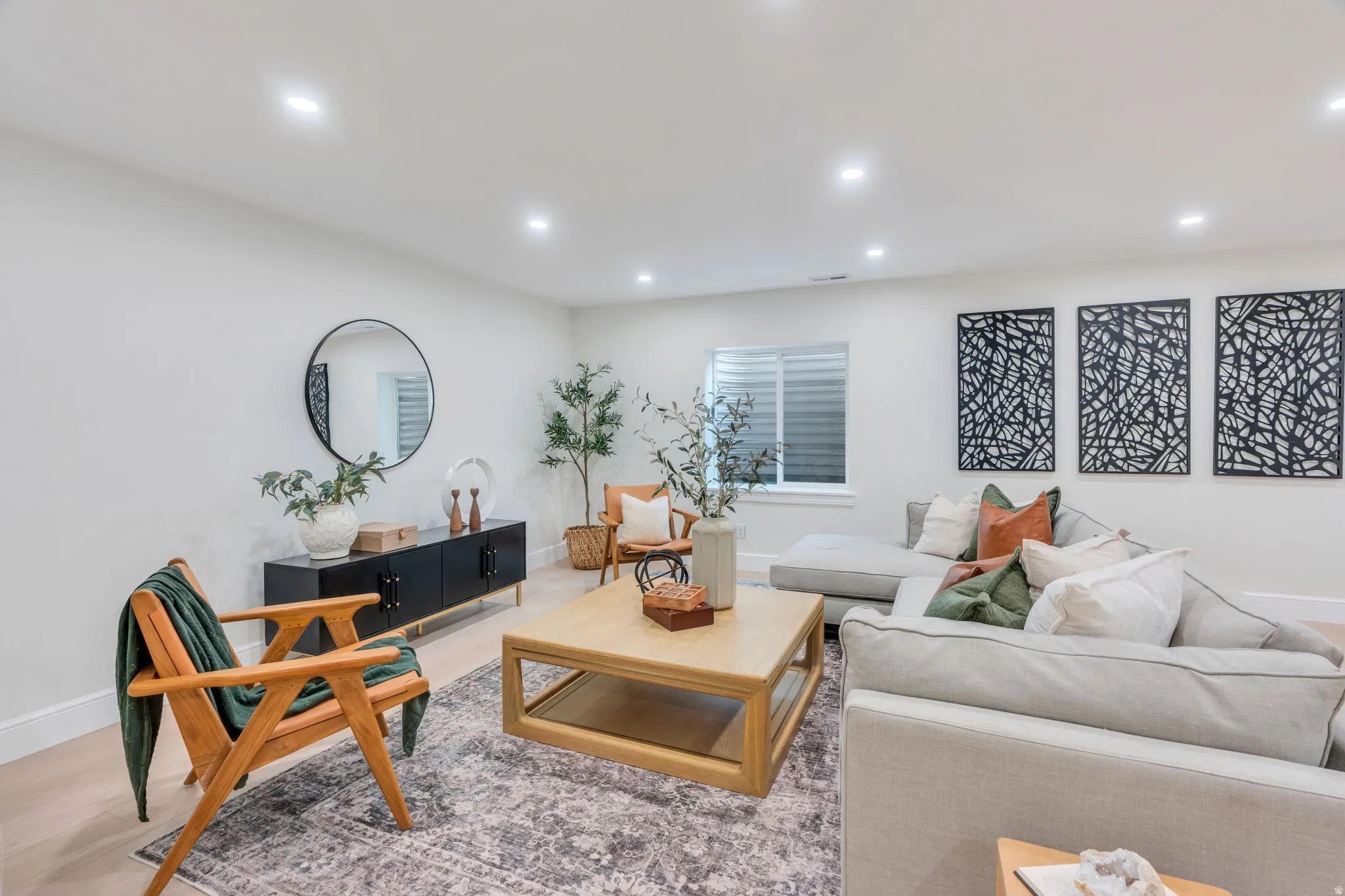 Spacious living area featuring light-toned walls, recessed lighting, and wood-finish flooring