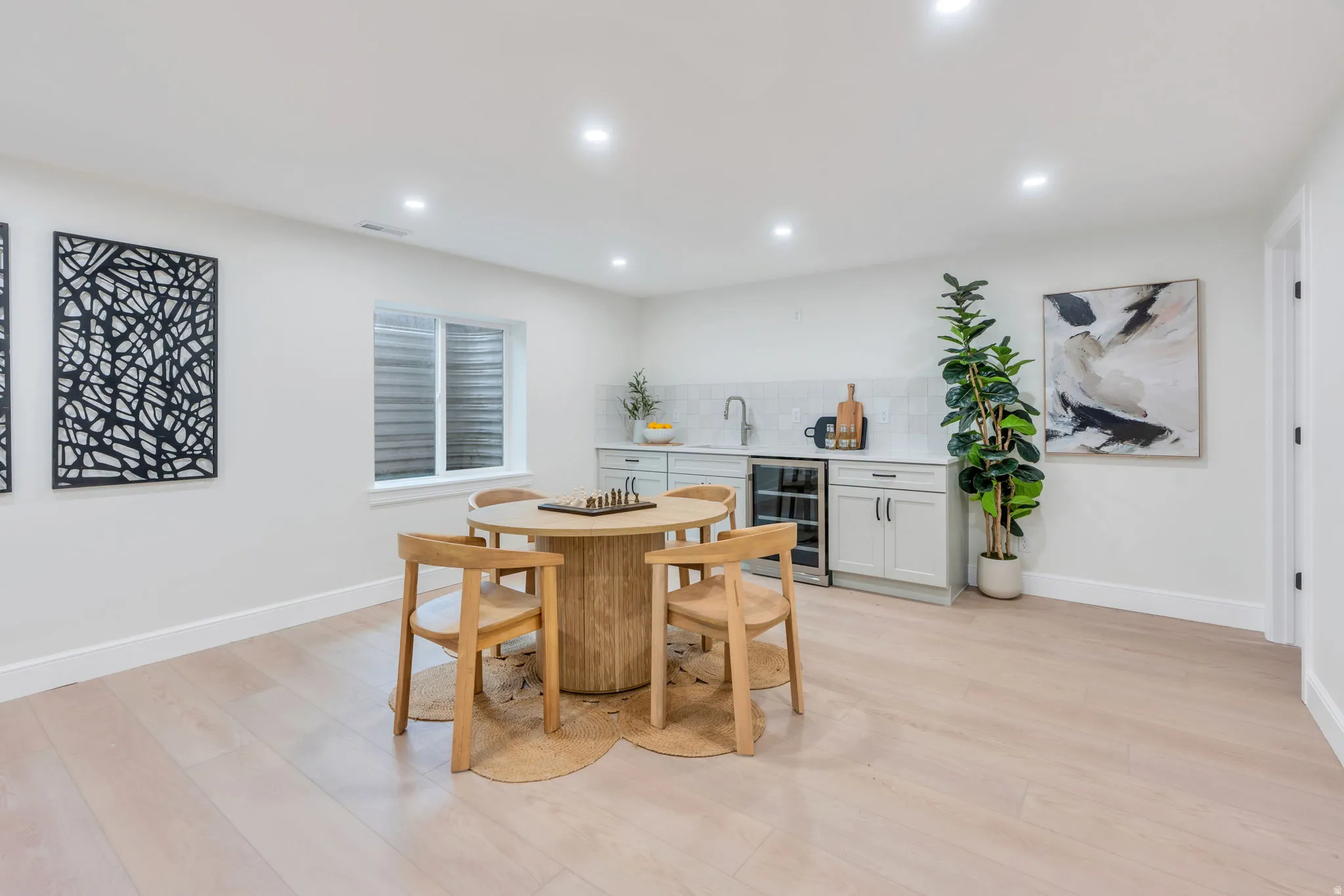 Spacious room featuring light wood-finish flooring, recessed lighting, and a built-in wet bar with a beverage cooler