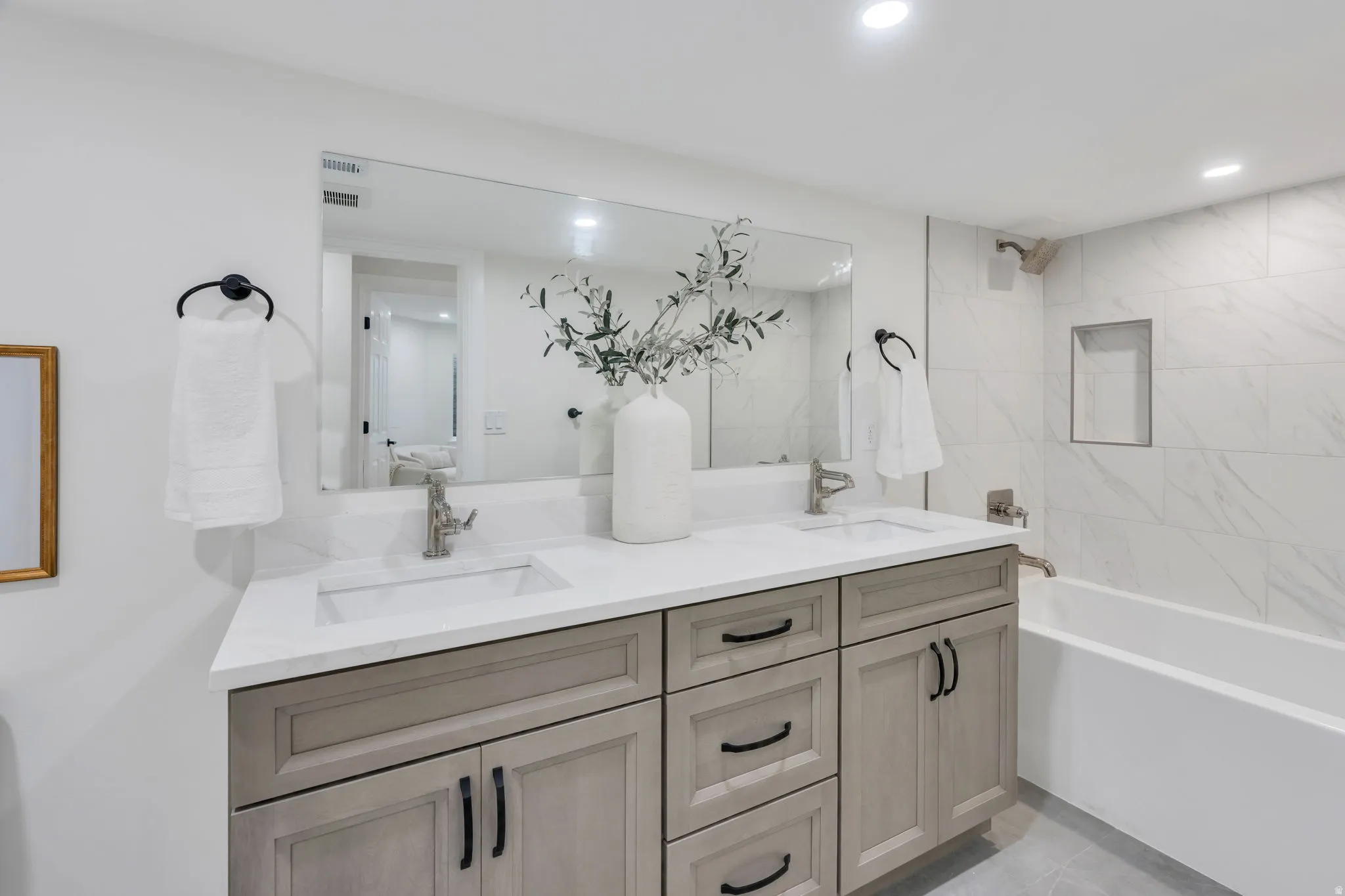 Bathroom featuring a double vanity with light-toned cabinetry, integrated sinks, and a large mirror