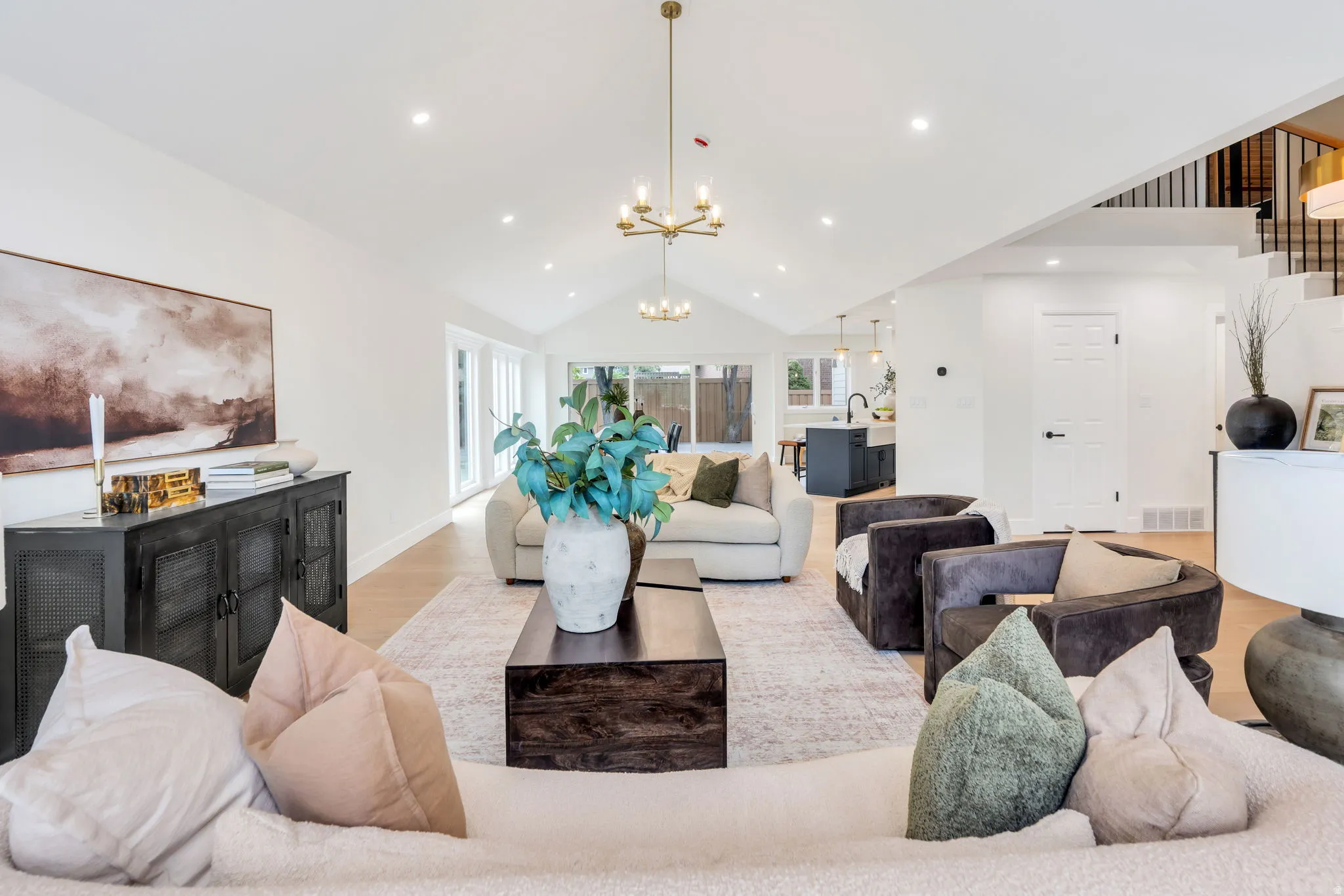 Vaulted ceilings with recessed lighting, light wood-finish flooring, and a contemporary chandelier