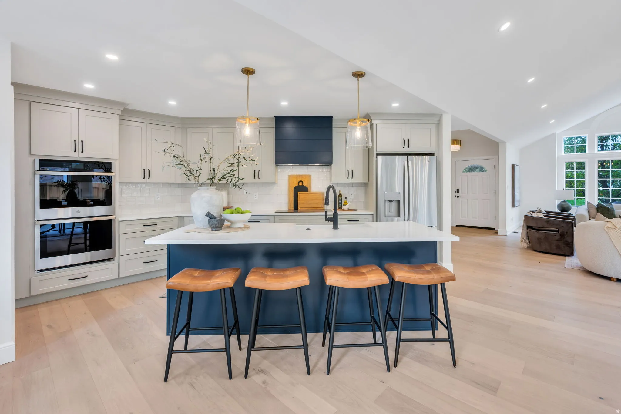 Modern kitchen featuring a large central island with seating, white countertops, and a subway tile backsplash