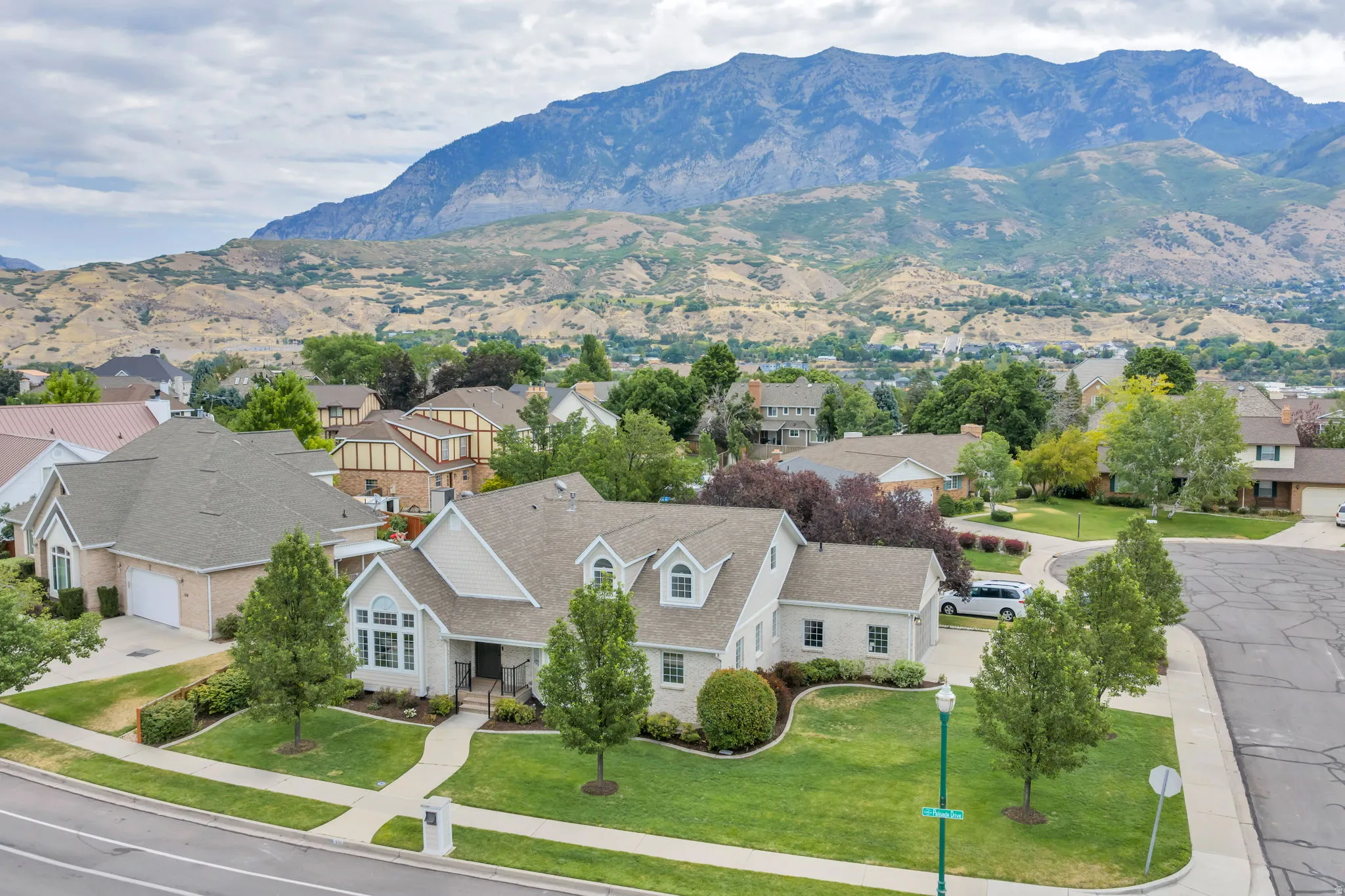 Traditional-style residence featuring a prominent mountain backdrop, lush green landscaping, and mature trees