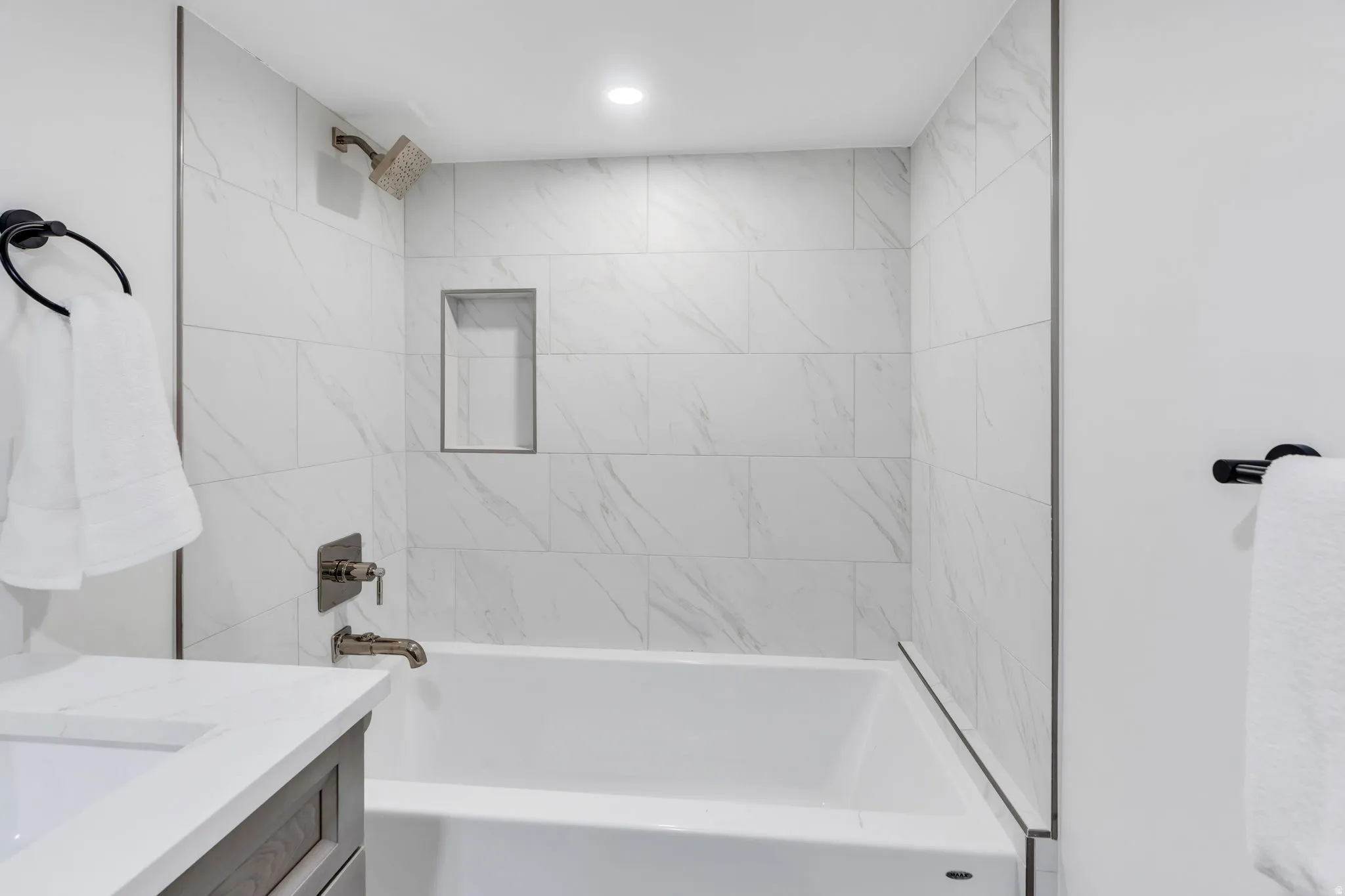 Bathroom featuring a full-size bathtub, white subway tile surround, built-in shower niche, recessed lighting, and brushed nickel fixtures