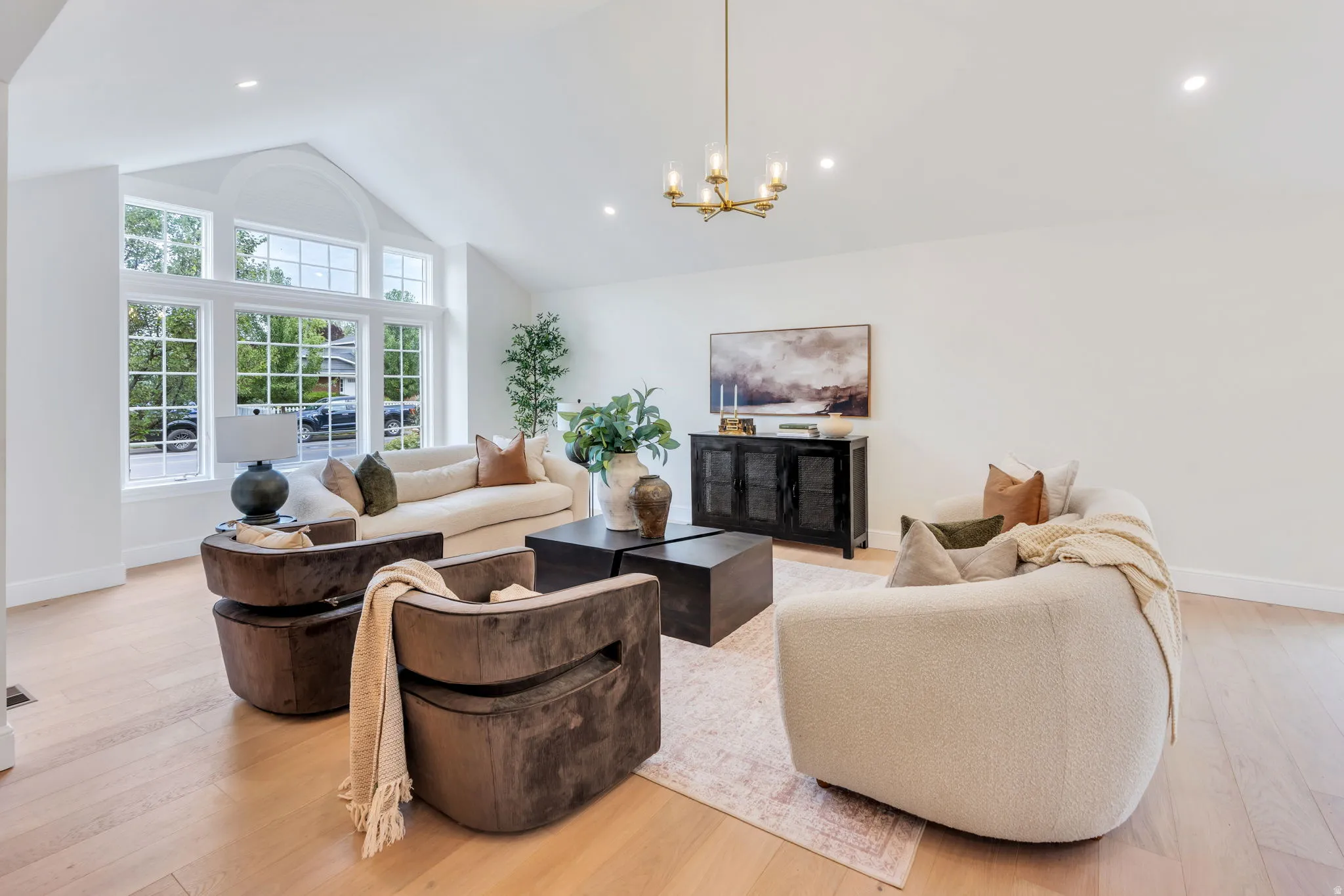 Vaulted ceiling living space featuring a large arched window array, recessed lighting, and wood-finish flooring