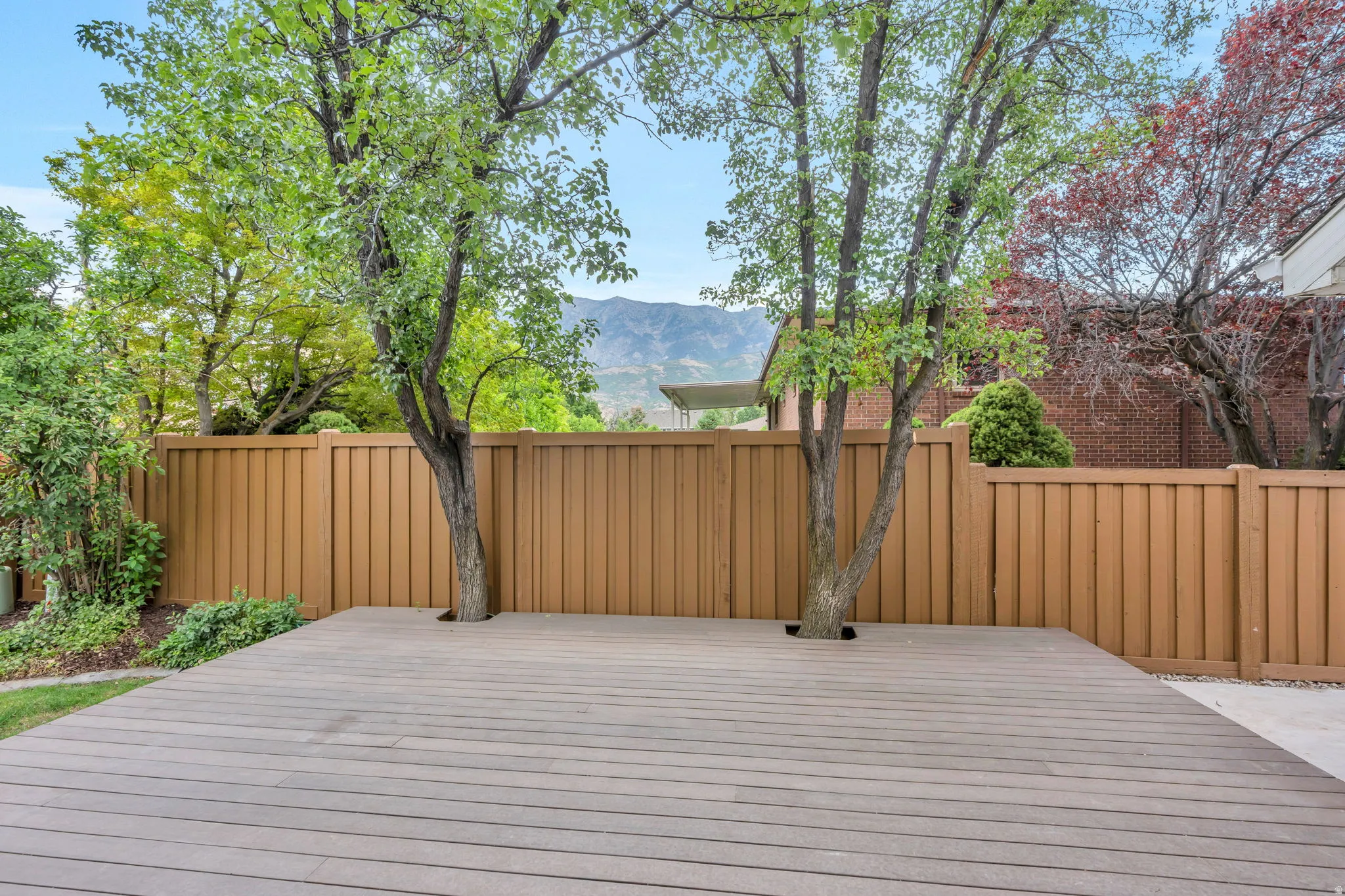 Spacious outdoor deck featuring composite decking and integrated trees
