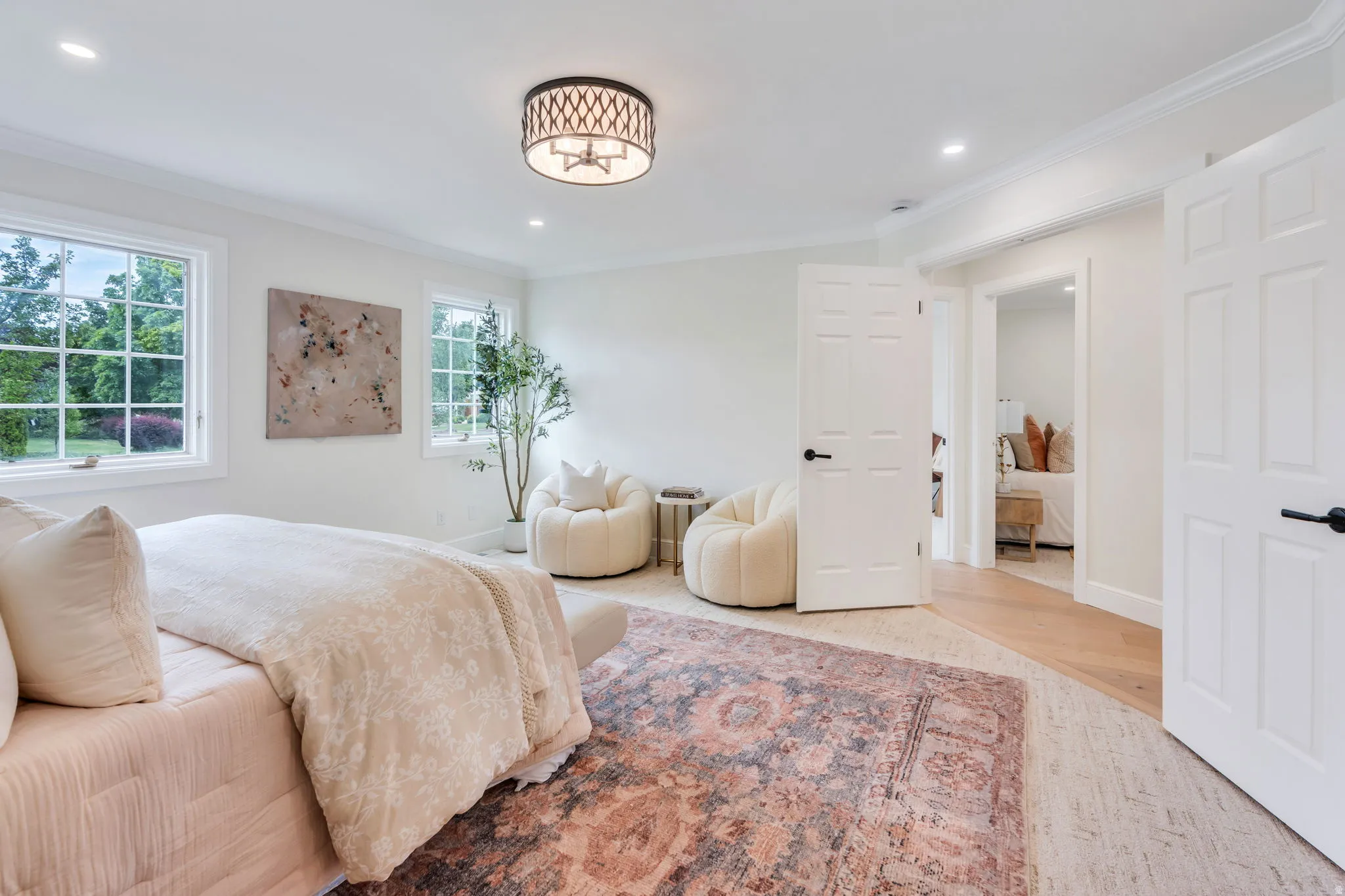 Bright interior space featuring multiple windows with grid patterns, a drum pendant light fixture, recessed ceiling lighting, crown molding, and two paneled doors with black hardware