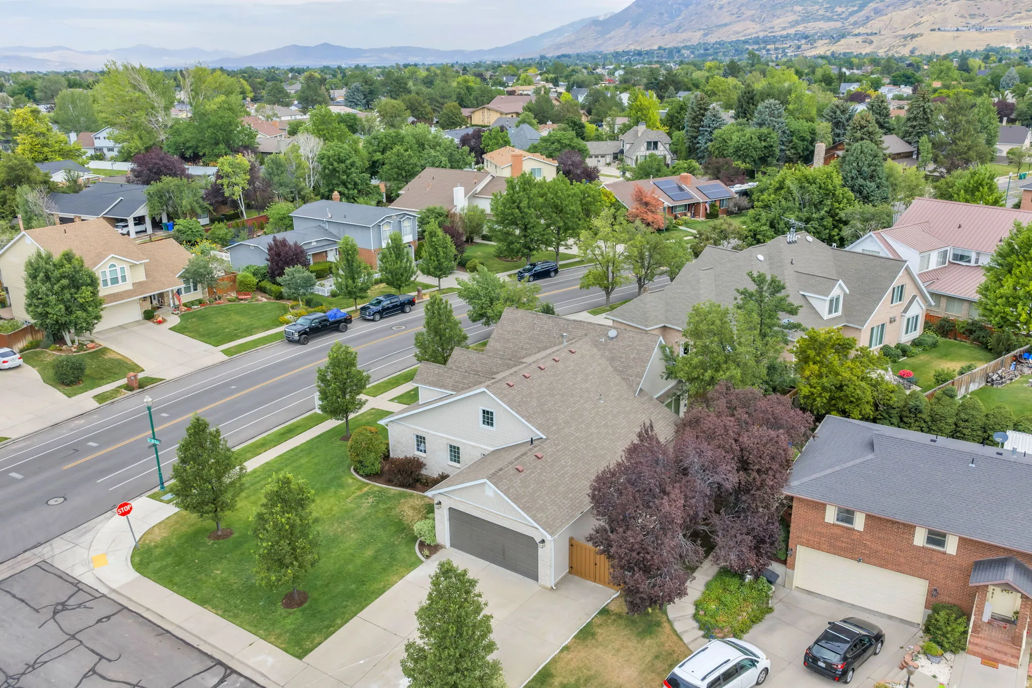 Residential property featuring a two-car garage, mature landscaping, and a paved driveway