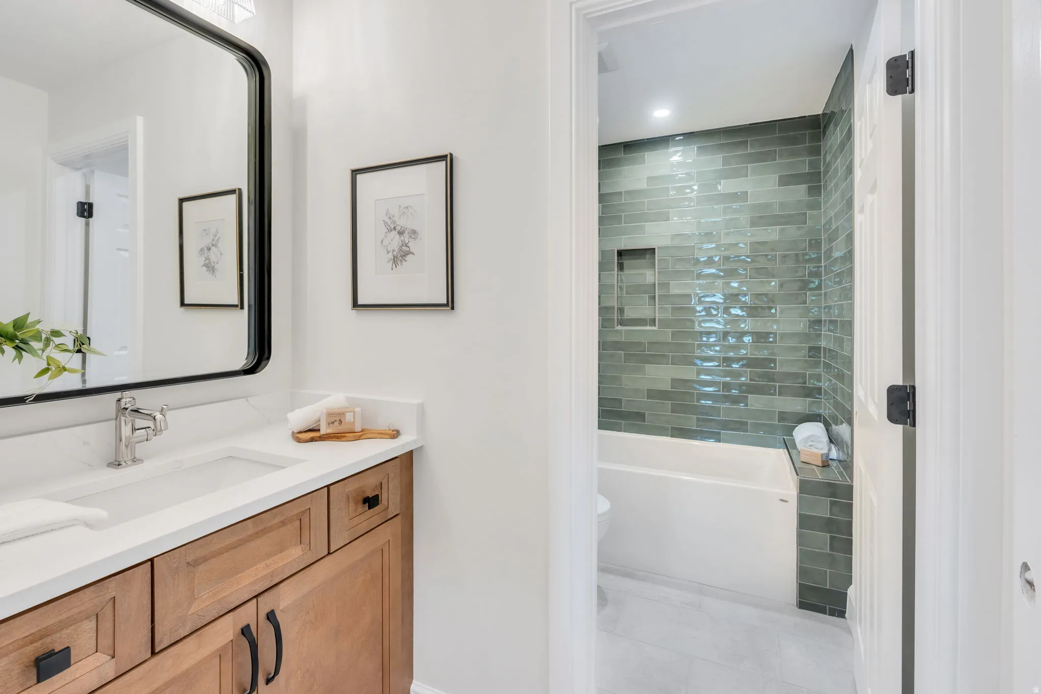 Bathroom vanity with a white rectangular undermount sink, chrome faucet, and wood-finish cabinetry featuring black hardware