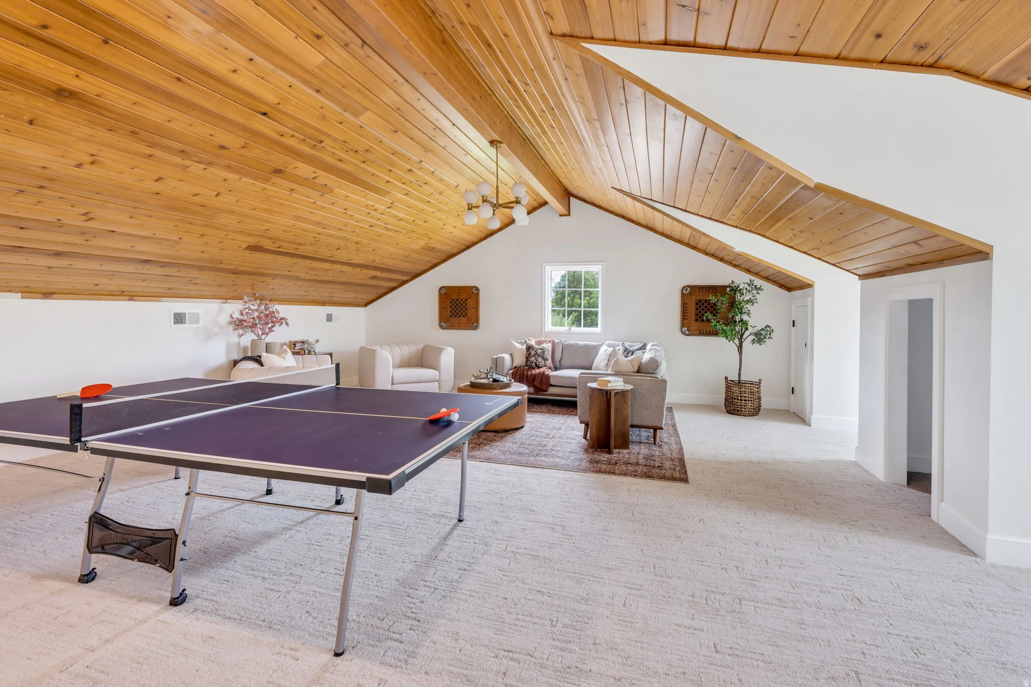 Expansive bonus room featuring a pitched wood-paneled ceiling, recessed window, and neutral-toned carpeting