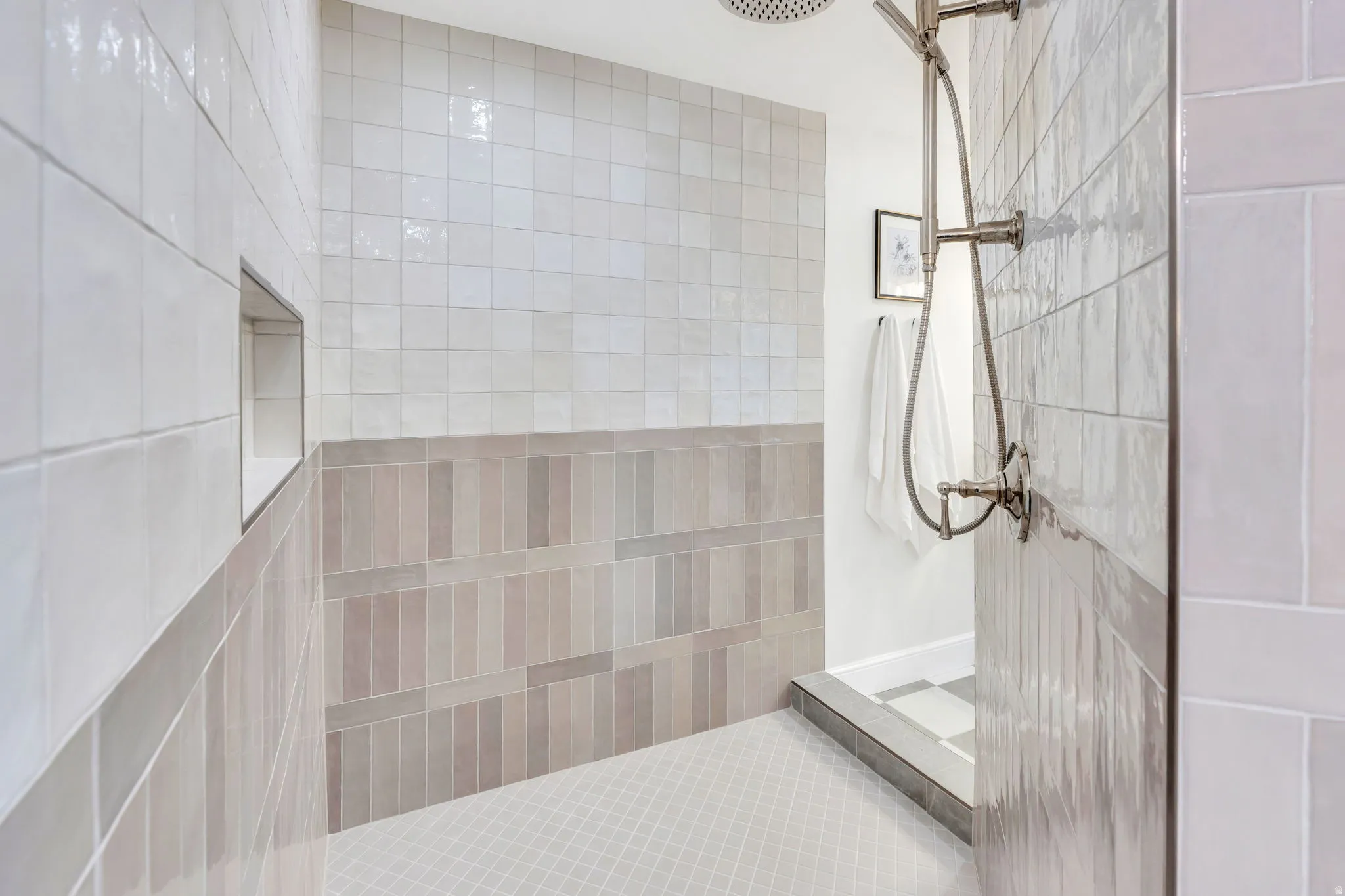 Walk-in shower with a rainfall showerhead, handheld shower fixture, recessed tile niche, and a combination of square and rectangular wall tiles