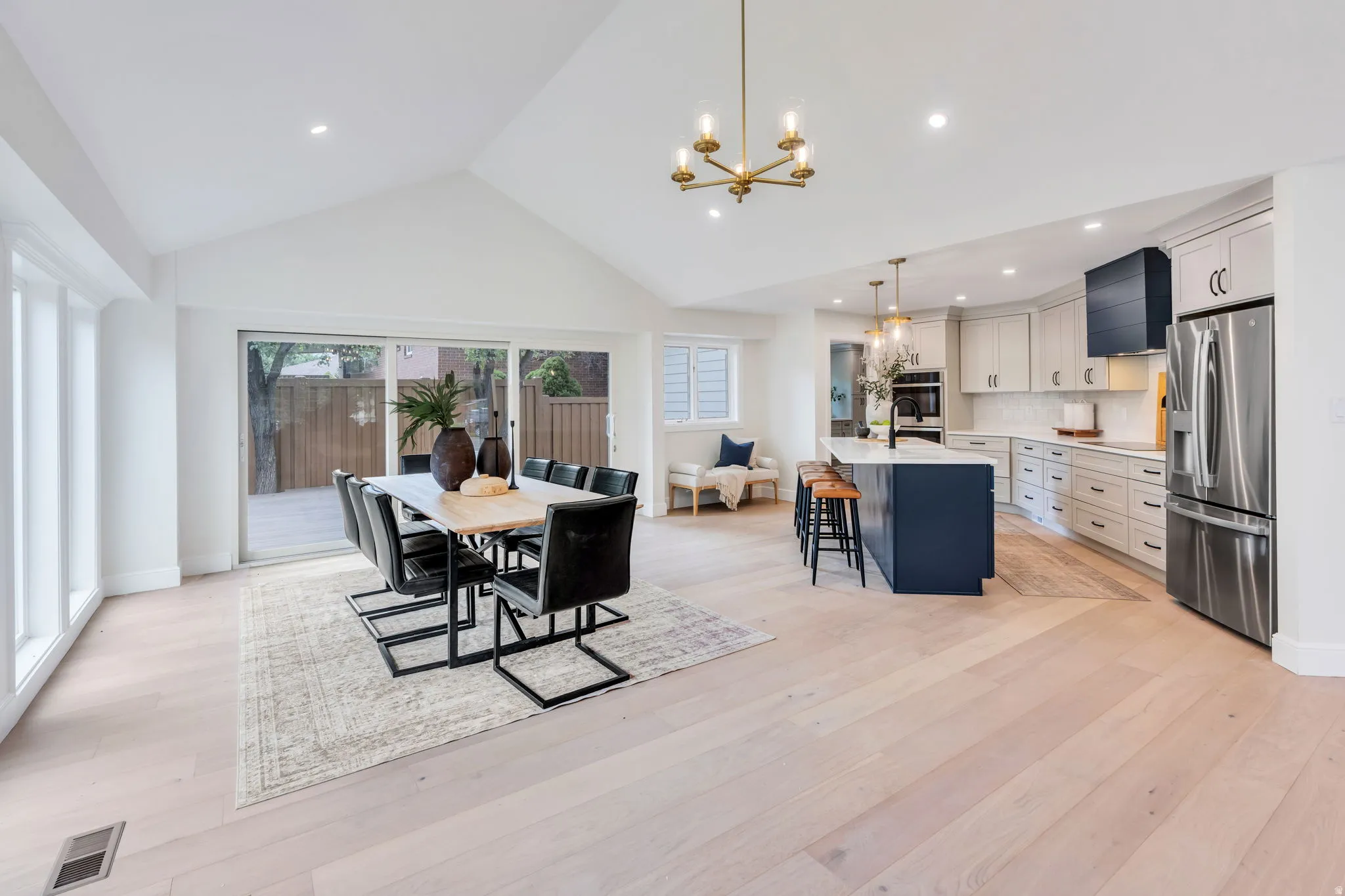 Spacious open-concept living area featuring a vaulted ceiling and light wood-finish flooring